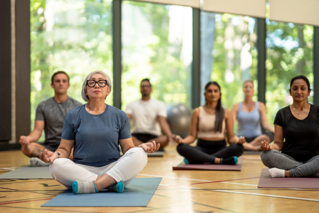 group of adults meditate in a gym